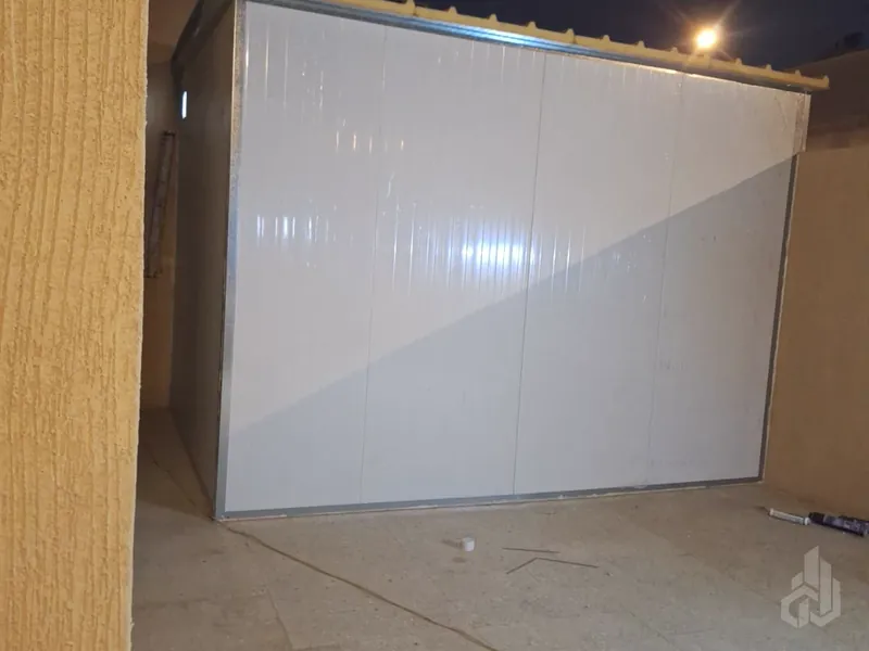 جدار مكسو بألواح ساندوتش بانل بيضاء في موقع ليلًا