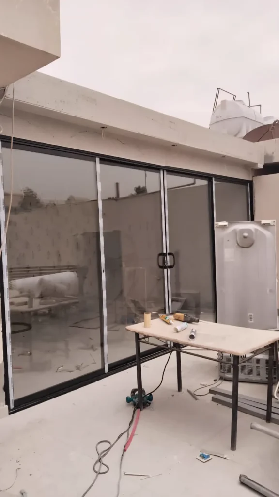 الجهة الداخلية لملحق بواجهة زجاجية وإطارات ألمنيوم سوداء أثناء أعمال التشطيب