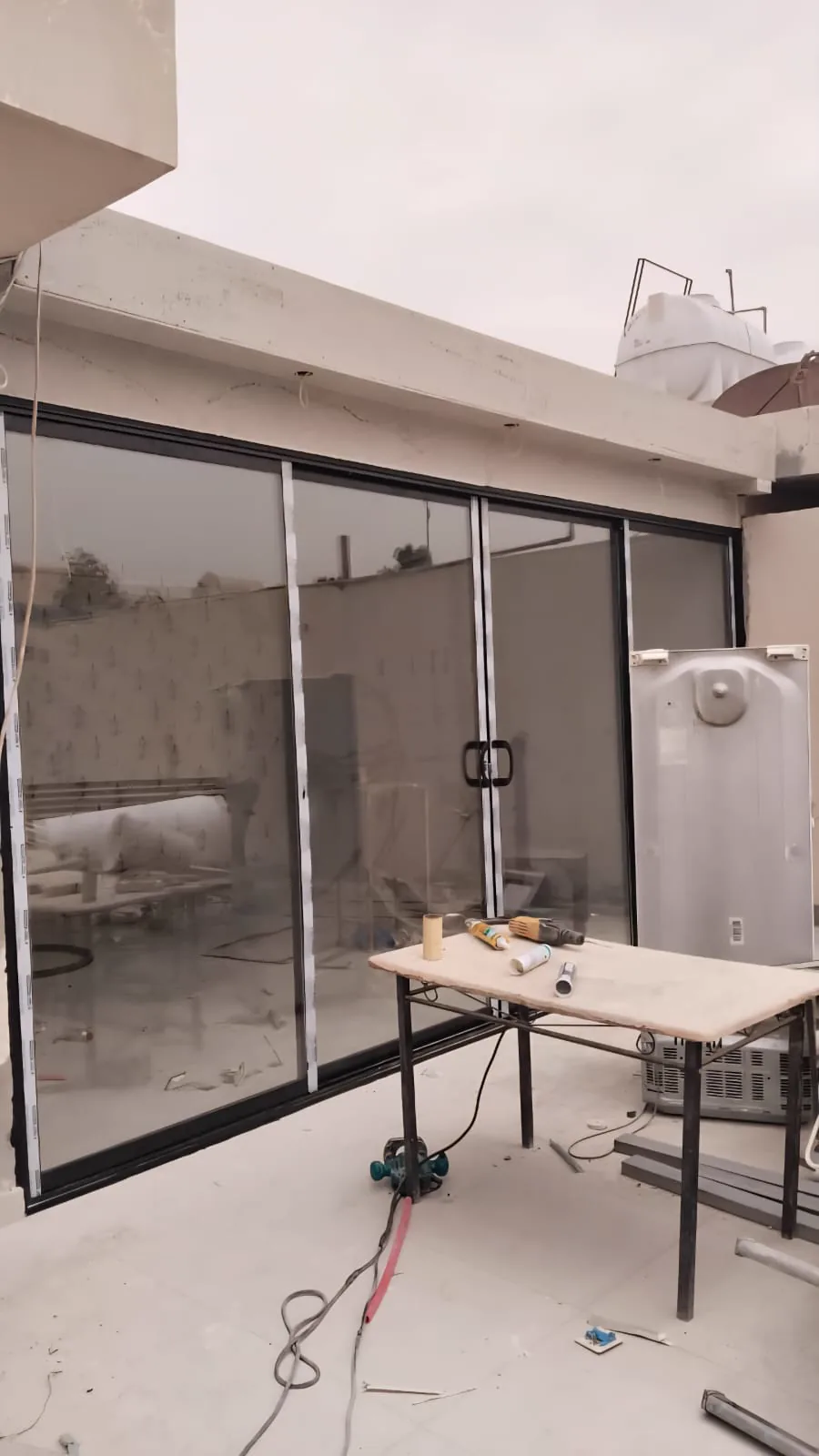 الجهة الداخلية لملحق بواجهة زجاجية وإطارات ألمنيوم سوداء أثناء أعمال التشطيب