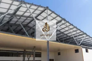 الوجه السفلي لسقف من ألواح معزولة مثبّت على جمالونات معدنية أعلى جدران من الألواح في منشأ مفتوح