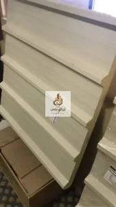 ألواح ساندوتش بانل بلون كريمي مكدّسة بشكل مائل تُظهر حافة التعشيق وبطاقة بيانات ملصقة على أحد الألواح