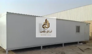 وحدة طويلة من ألواح الساندوتش بانل بوجه أبيض مرفوعة على قواعد معدنية وبها نافذة وباب في موقع عمل