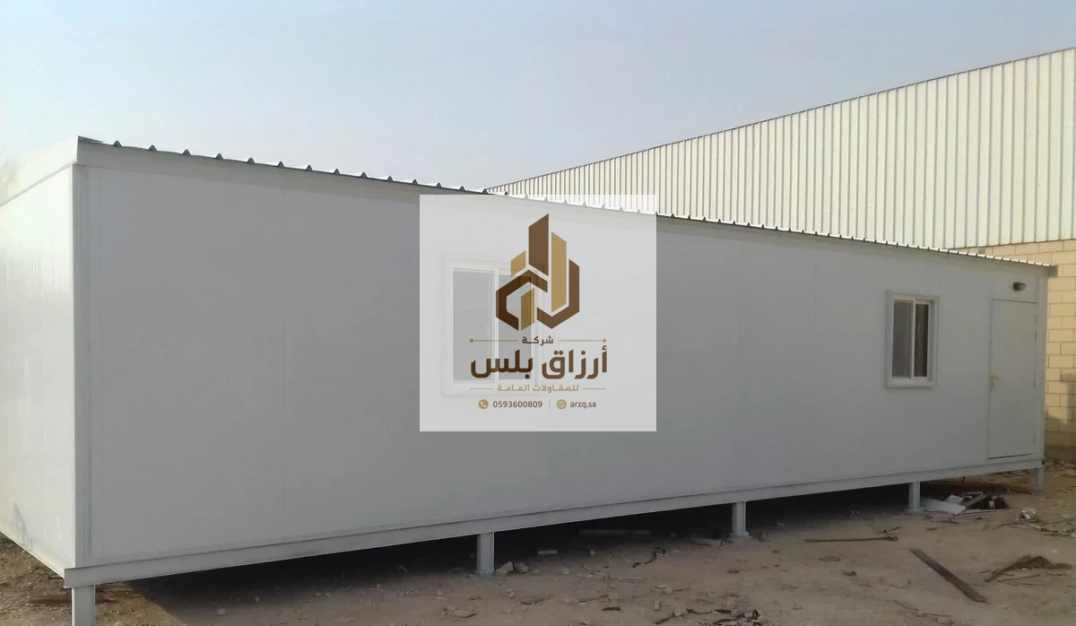 وحدة طويلة من ألواح الساندوتش بانل بوجه أبيض مرفوعة على قواعد معدنية وبها نافذة وباب في موقع عمل
