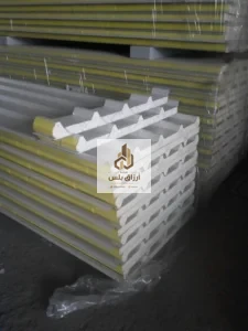 ألواح ساندوتش بانل مكدّسة ومغلّفة بالبلاستيك يظهر في حوافها قلب من الصوف المعدني الأصفر بين وجهين معدنيين مضلّعين