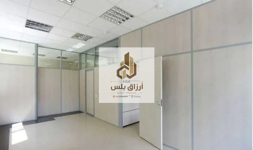 فراغ مكتبي داخلي بقواطع من ألواح معزولة وتقسيمات زجاجية وسقف مستعار وباب مفتوح