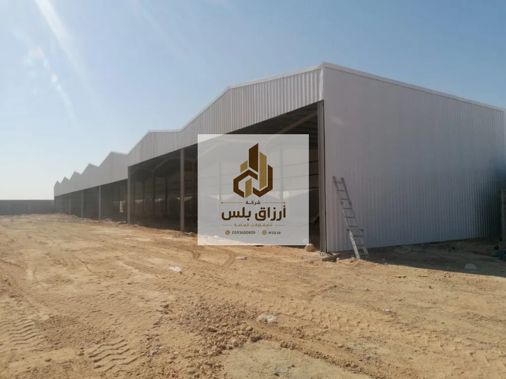 هنجر واسع مفتوح من الجانب بكسوة ألواح معزولة على هيكل معدني في موقع ترابي مع سلّم مستند إلى الواجهة