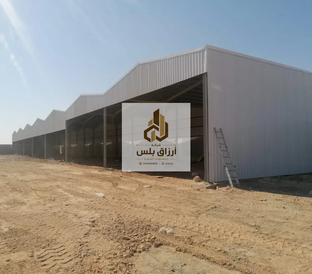 هنجر واسع مفتوح من الجانب بكسوة ألواح معزولة على هيكل معدني في موقع ترابي مع سلّم مستند إلى الواجهة