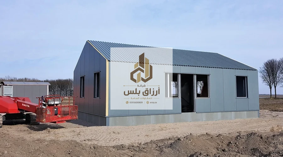 مبنى من ألواح معزولة بكسوة رمادية مضلّعة وسقف جمالوني بنوافذ وباب مع معدّة تنفيذ في الموقع