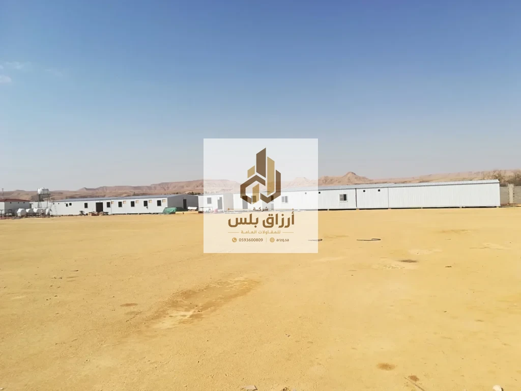 صف طويل من وحدات جاهزة من ألواح معزولة على أرض صحراوية واسعة وجبال في الخلفية