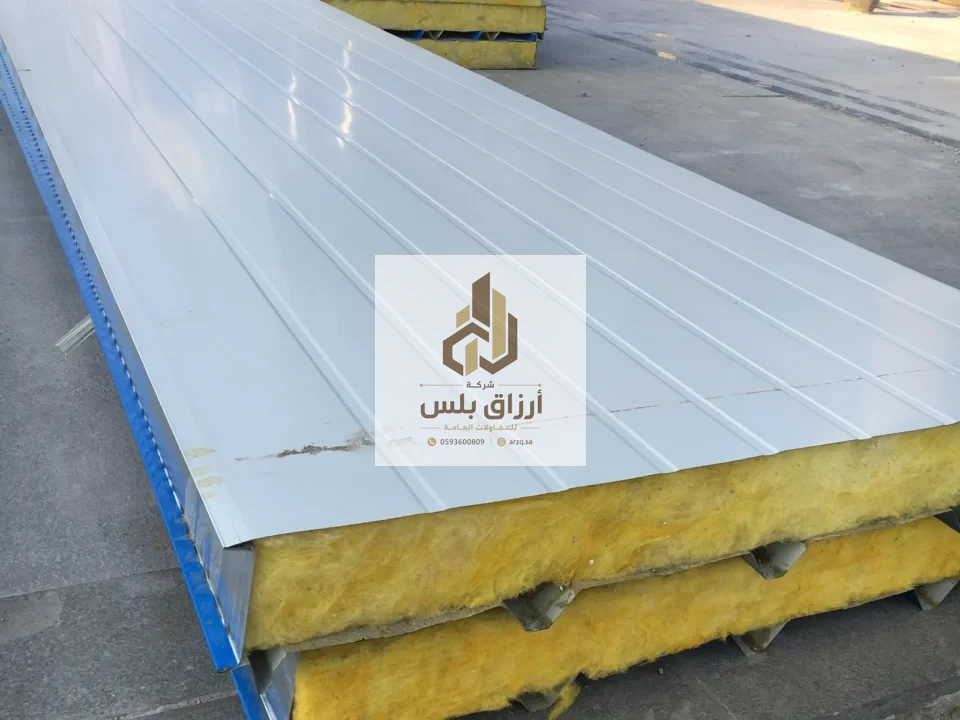 لقطة قريبة كبيرة لألواح سقف معزولة يظهر في حوافها قلب من الصوف المعدني الأصفر فوق حمّالة معدنية زرقاء