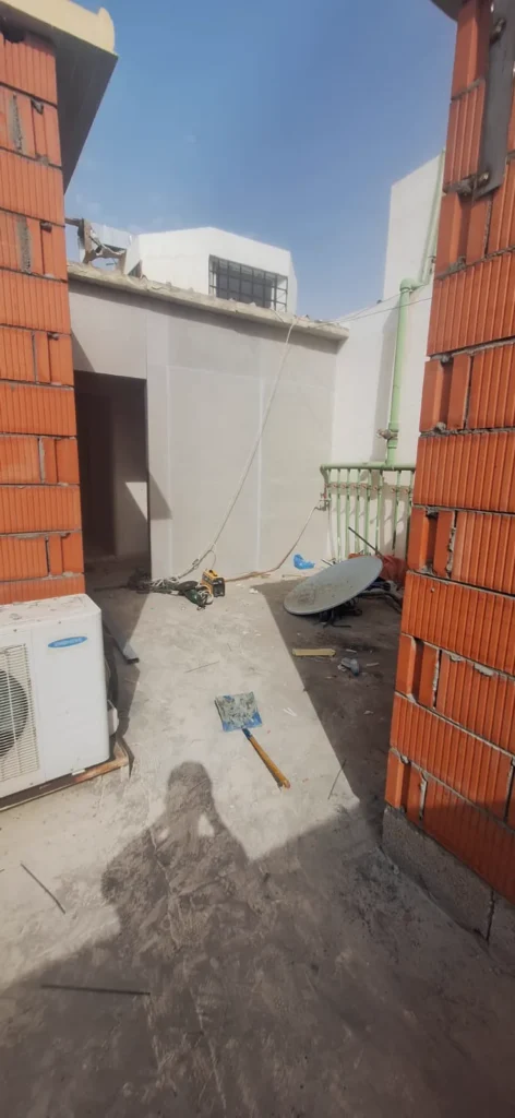 فناء مكشوف على سطح بين مبنيين مع وحدات تكييف على الجدار