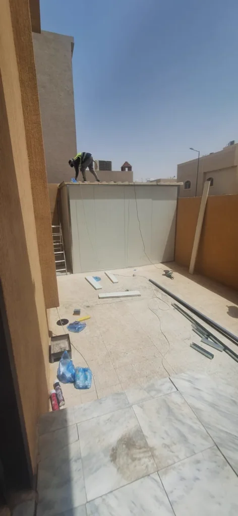 سطح مبنى أثناء تنفيذ غرفة، وتظهر ألواح ومواد التركيب موزّعة على الأرضية