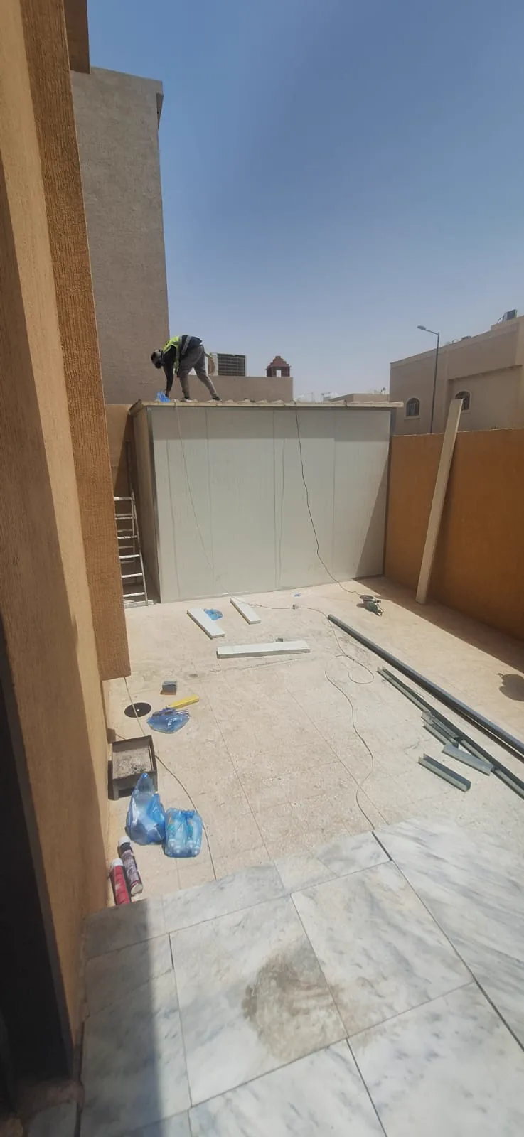 سطح مبنى أثناء تنفيذ غرفة، وتظهر ألواح ومواد التركيب موزّعة على الأرضية