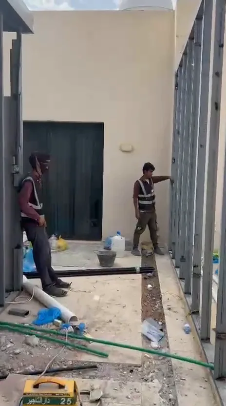 ممر خارجي بين غرف ساندوتش بانل مع أبواب مركّبة وجدران منتهية