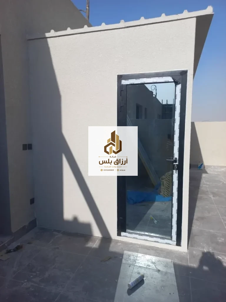 غرفة ساندوتش بانل على سطح، بابها من الألمنيوم والزجاج وتظهر حافة السقف المائلة أعلى الجدار
