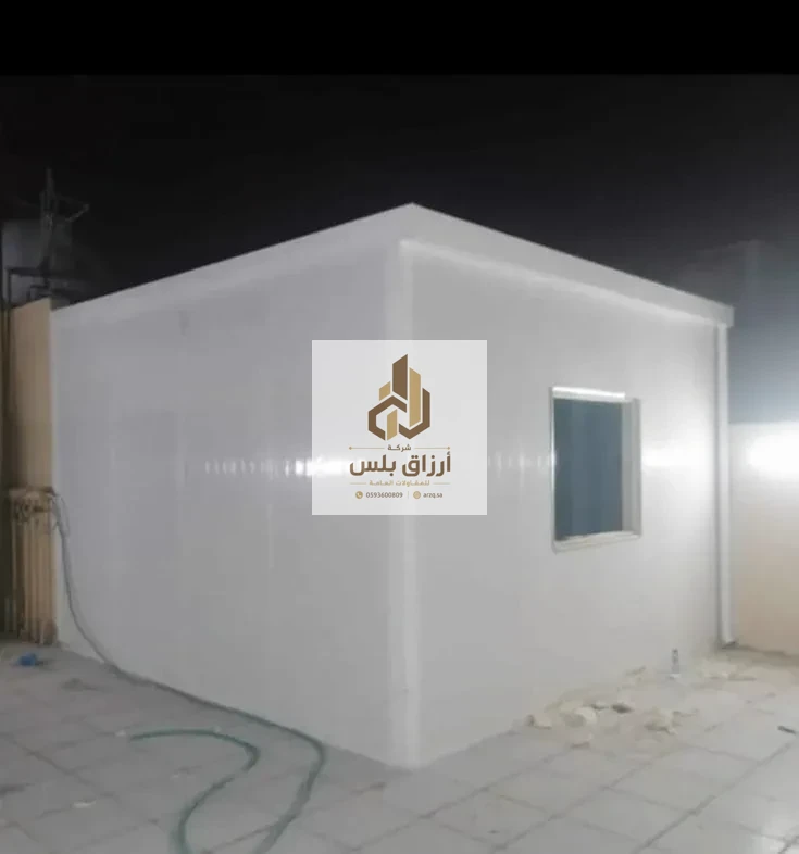 غرفة ساندوتش بانل بيضاء مصوّرة ليلًا، تظهر نافذتها الصغيرة واستقامة وصلات الألواح على الجدار