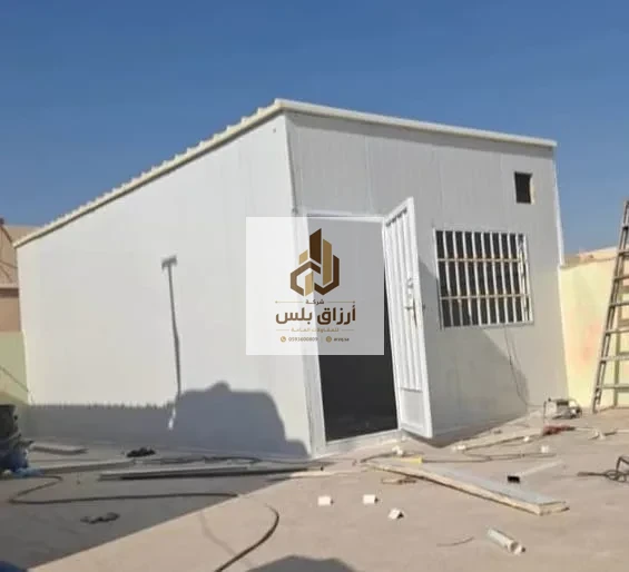 جدار غرفة ساندوتش بانل تظهر فيه نافذة مركّبة خلفها شبك حماية معدني