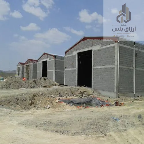 صف مستودعات صغيرة بجدران بلوك وأسقف حديدية جمالونية قيد الإنشاء