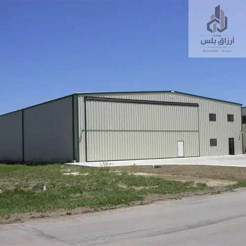 هنجر معدني بباب منزلق واسع على أرض عشبية