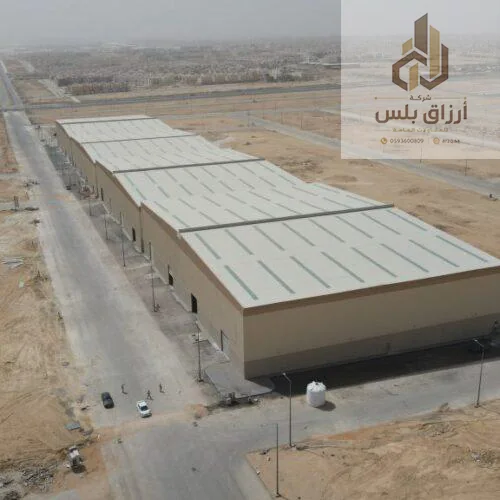 منظر جوي لمستودعات حديدية طويلة بأسقف معدنية في موقع صحراوي