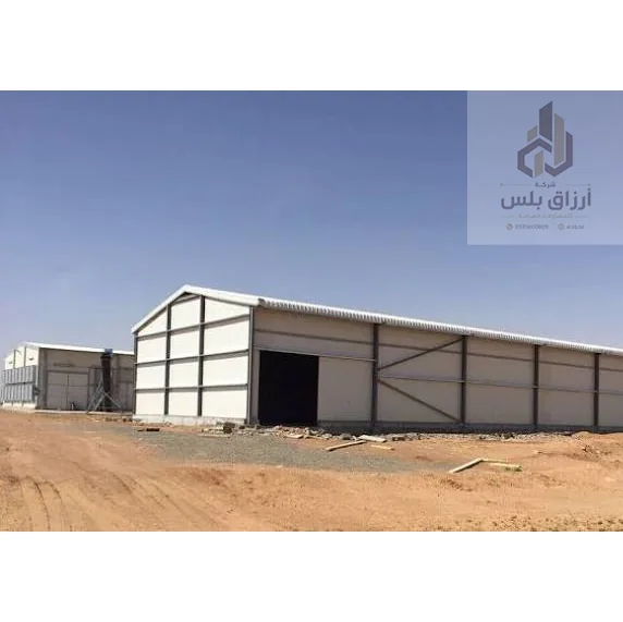 هنجر حديد صغير بواجهة ألواح معدنية وفتحة باب في موقع رملي