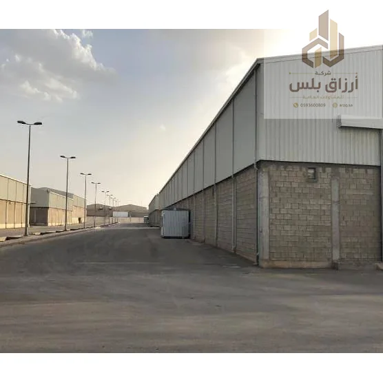 مستودع طويل بهيكل حديدي وقاعدة من البلوك على امتداد شارع بإنارة